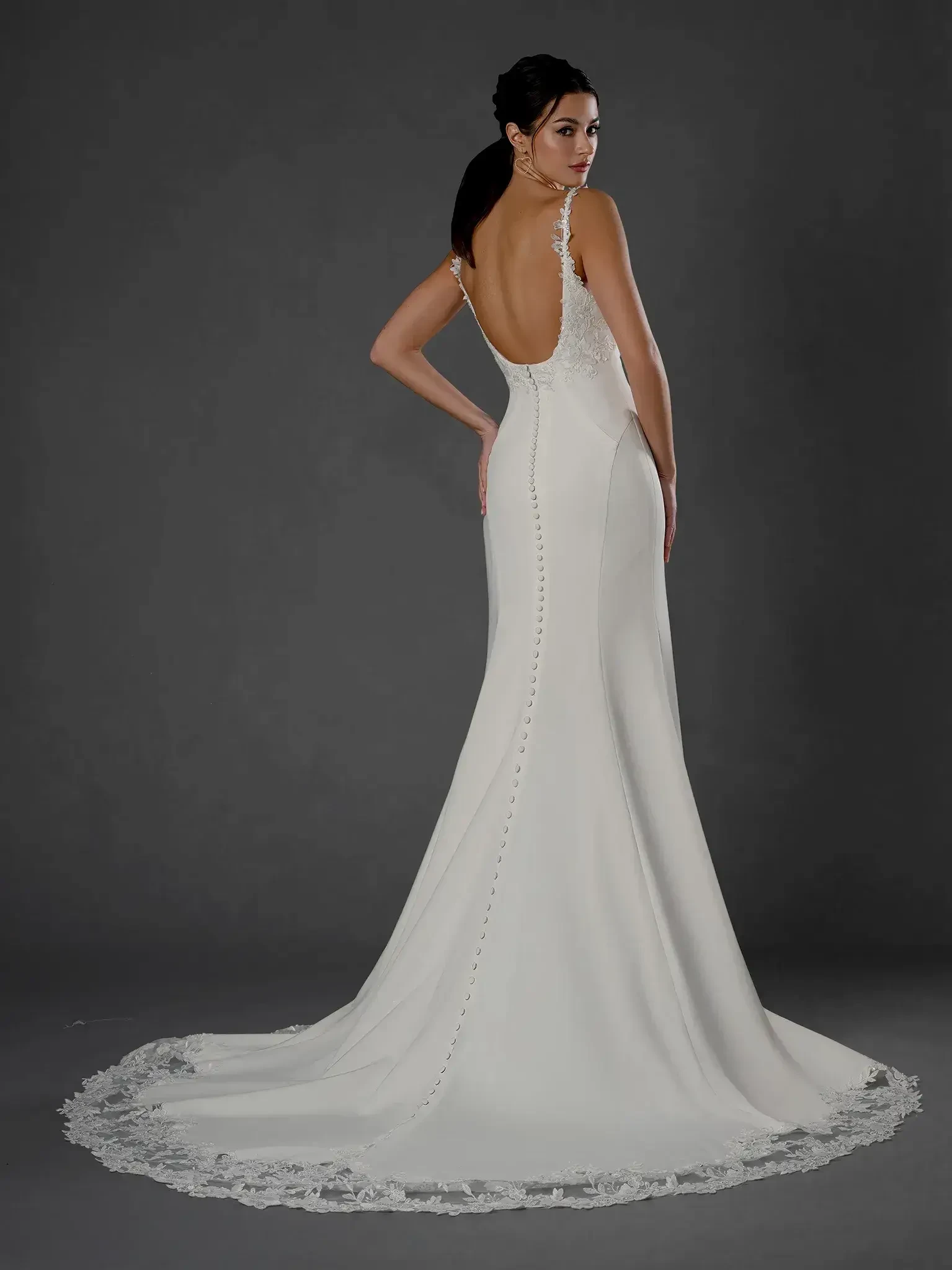 model is wearing a sleeveless fit and flare wedding dress with a low back