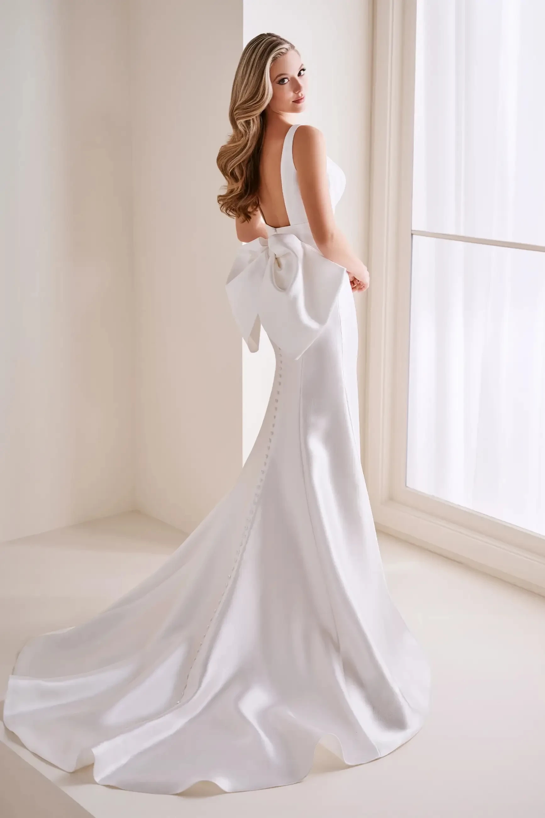 Model is wearing a Mikado mermaid wedding dress with a timeless sweetheart neckline and a detachable back bow.