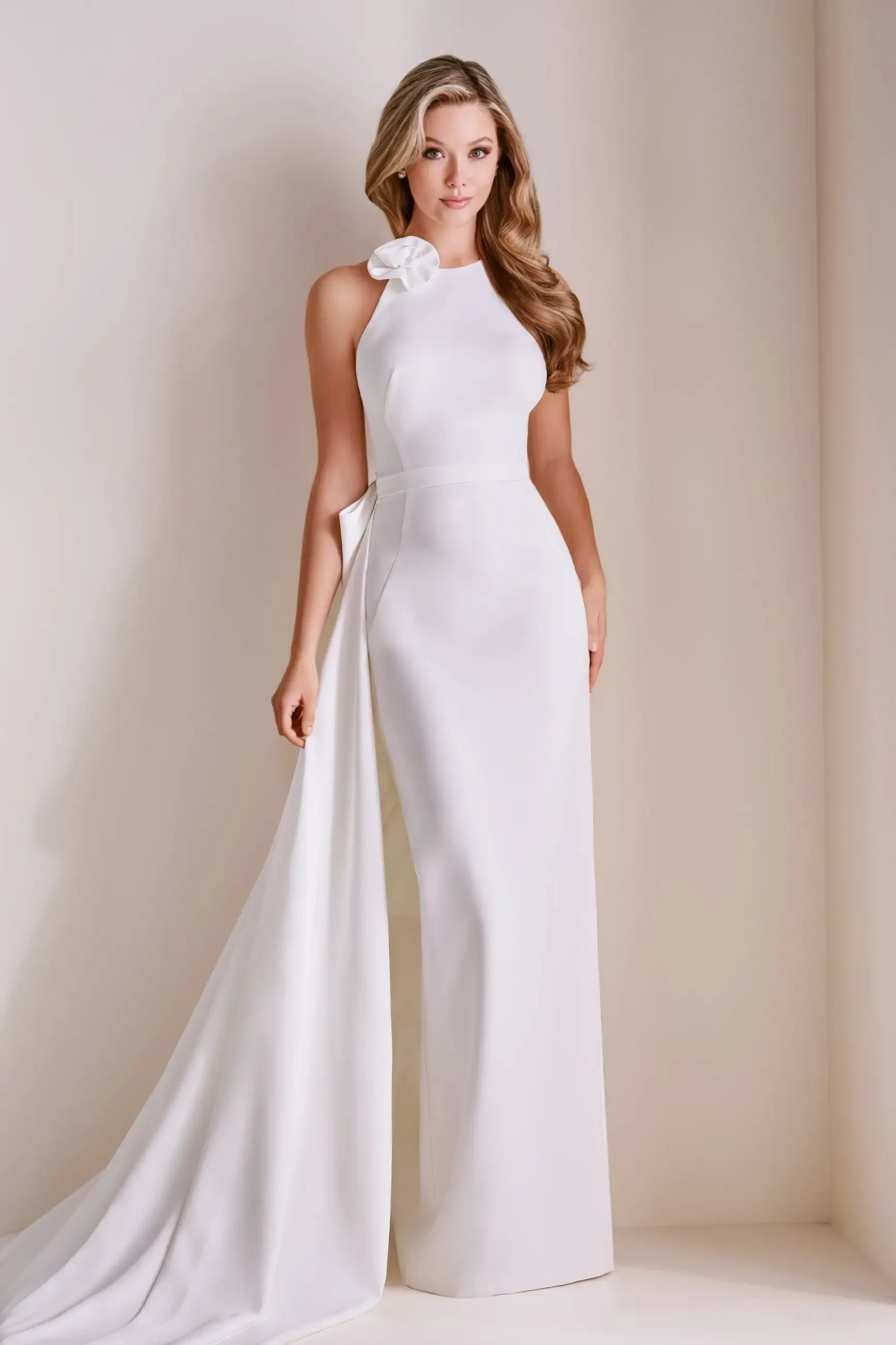 Model is wearing a sleek sheath gown with a high neckline, 3D flower accent, and a detachable 82-inch train.