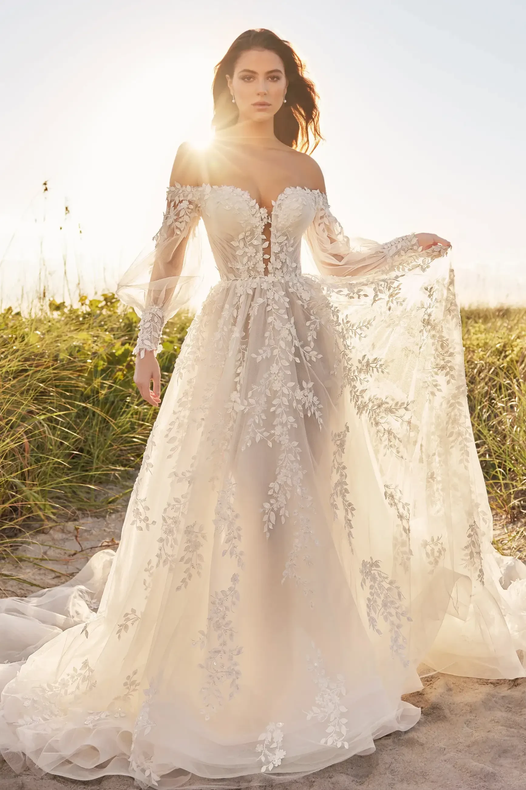 model is wearing an off the shoulder long sleeve lace wedding gown